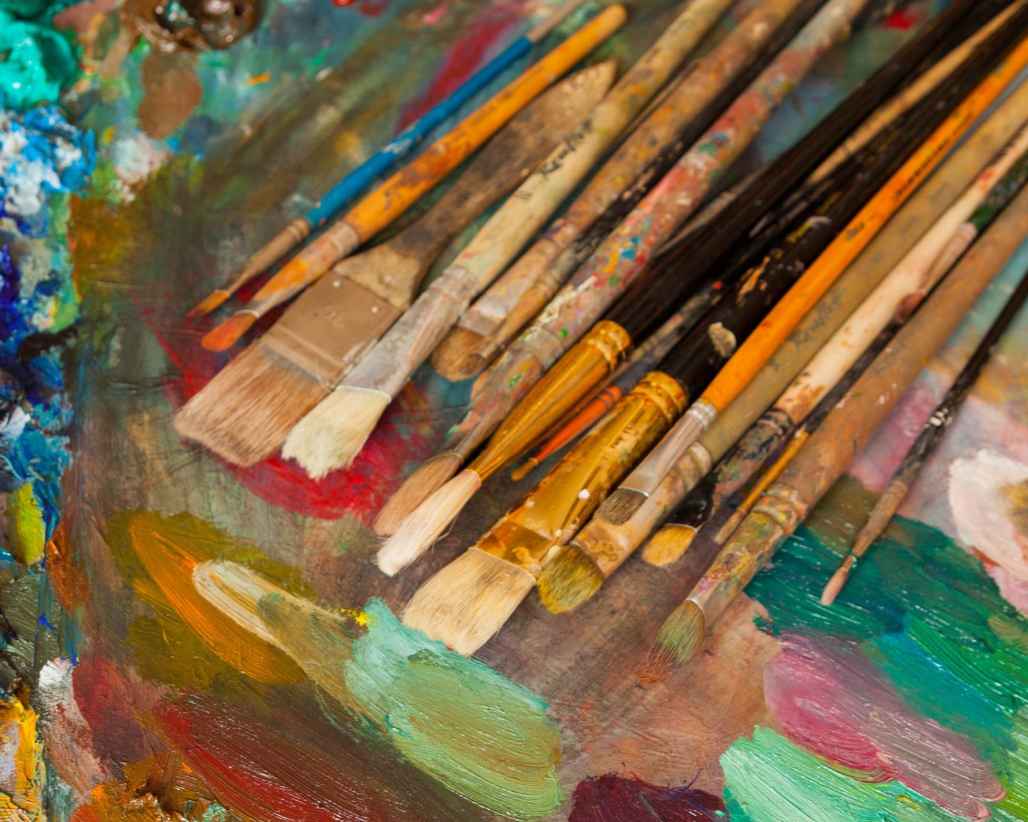 Paints, brushes and palette on the wood background. The workplace of the artist. Banner for school