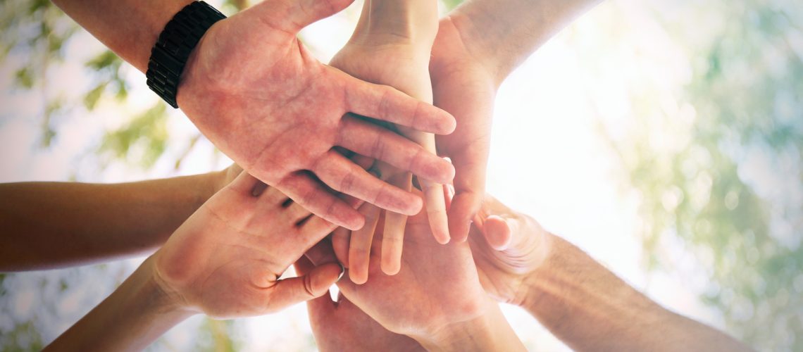 Hands of young people close up on sunny nature background